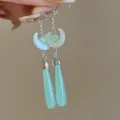Detalle de pendientes largos de estilo chino con diseño de luna y colgante verde. - Pendientes colgantes de salida de luna sobre el mar
