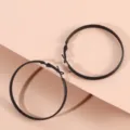 Gros plan sur de grandes boucles d'oreilles créoles noires mates, design moderne et élégant. - Noir