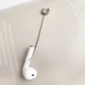 Primer plano detalle del manguito de oreja con cadena anti-pérdida de acero inoxidable. - Estilo Botón / Pieza Única