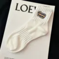 White ribbed mid-tube socks featuring a cute embroidered choose happy patch detail close up. - One Size / Cream White