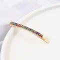 Close-up detail of a Korean style gold-toned bobby pin featuring sparkling multi-colored rhinestones. - Curved Hair Clip / Gold Multicolor Zircon