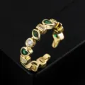 Gros plan de la bague ouverte plaquée or vintage avec des zircons verts et blancs. - Style D