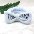 Nahaufnahme eines weichen blauen Plüsch-Make-up-Stirnbandes mit süßen OMG-Stickereidetails. - Hellblaue Flanell-Haarbänder
