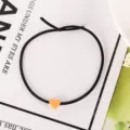 Nahaufnahme des schwarzen elastischen Haargummis mit einem orangen Herz-Anhänger. - 1# Gelbe Haargummis mit kleinem Herz