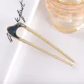 Detail view of a modern minimalist U-shaped hair fork in matte gold metal with chic dark accent. - 10.9cm / Gray