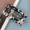 Minimalistische rechthoekige acetaat haarspeld met zwart-wit patroon en metalen veer. - Acetaat Veerklem / Zwart Wit Geblokt