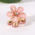 Detailaufnahme einer rosa Blumen Haarklammer mit Strasssteinen und goldenen Metallzähnen. - 2.1cm / Pfirsichrosa Strass Pflaumenblüte