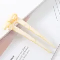 Close-up detail of the elegant acetate U-shaped hair stick featuring a hollow bow design. - Bowknot Hair Fork / Yellow