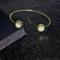 Vista detallada de una pulsera abierta dorada decorada con circonitas redondas brillantes. - Estilo Diamante Redondo / Dorado