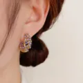 Primer plano detallado de pendientes de aro dorados con pedrería morada brillante. - Estilo de Diamante de Imitación Púrpura / Púrpura