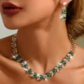 Vista dettagliata di un lusso set di gioielli da sposa con collana e orecchini strass verde. - Collezione Lusso Foglia Vite (80803727)