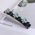Gedetailleerde close-up van een zwarte dubbellaagse haarklem met turquoise vlinders. - #11 Dubbellagige strass eendenbekclips voor vlechtwerk
