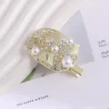 Exquisite detail close-up of a Korean style metal hair clip adorned with pearls and rhinestones. - Leaf Rhinestone Duckbill Clip / Gold