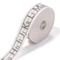 Detailed view of white cotton ribbon roll with alphabet pattern for gift wrapping and crafts. - Letter Style / Single Roll
