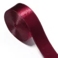 Close-up detail of dark red shiny ribbon roll, premium glitter fabric trim for crafts. - Burgundy