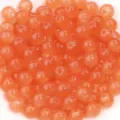 Gros plan détaillé de perles rondes en verre orange vif pour la création de bijoux artisanaux. - Orange