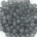 Gros plan détaillé de perles rondes en verre translucide gris pour vos créations de bijoux DIY. - Gris