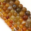 Primo piano dettagliato di perline tonde in agata crepata naturale, perfette per gioielli. - 6mm / Agata Venatura del Drago Ambra