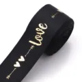 Black ribbon with gold foil love print for gift wrapping and DIY crafts detail view. - Black