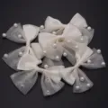 Detail shot of white ribbon bows with mesh tulle and pearl accents for DIY crafts and hair accessories. - 6 Pieces/Pack / Beige