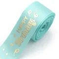 Close-up detail of light blue polyester ribbon with gold foil happy birthday print for gifts. - Green