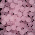 Gros plan détaillé de perles de verre rondes roses avec trous pour fabrication de bijoux DIY. - Rose