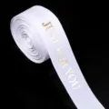 Λεπτομέρεια ρολού λευκής κορδέλας grosgrain με χρυσό κείμενο για συσκευασία δώρων. - Λευκό