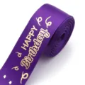 Purple gold stamped happy birthday ribbon roll, detailed view of satin fabric for gift wrapping. - Deep purple