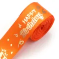 Close-up detail of orange ribbon with gold hot stamping Happy Birthday print for gift wrap. - Orange