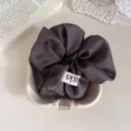 Minimalistische donkergrijze stoffen haarelastiek met klein label, zacht haaraccessoire. - Koffie
