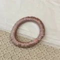 Nahaufnahme eines eleganten plissierten Satin Haargummis mit feiner glänzender Stoffstruktur. - Plissiertes Haargummi mit Perlen / Rosa