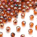 Dettaglio in primo piano di perline di cristallo ambrato sfaccettate con riflessi iridescenti. - Arancione Placcato Viola Rosso Rosa