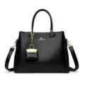 Black leather top handle handbag with shoulder strap and stylish metal charm for women daily use. - Black