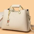 Elegante damestas met grote capaciteit, gouden handgreep en mooi hartvormig hangend. - Broken Wit