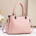 Primo piano dettagliato della borsa in pelle rosa elegante con finiture dorate e manici. - Rosa