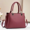 Vista dettagliata della borsa vintage in pelle rosso vino con dettagli metallici e doppi manici. - Rosso