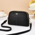 Vista dettagliata di una elegante borsa a tracolla in pelle nera con fiocco e zip dorate. - Modello due / Nero