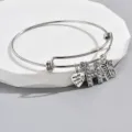 Close-up of adjustable silver wire bracelet featuring sparkling rhinestone letter H, heart and butterfly. - Style H