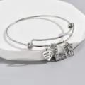 Close-up detail of silver adjustable bangle bracelet with love, letter L, and butterfly charms. - Style L