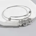Detail view of silver wire bangle with sparkling rhinestone letter S and butterfly charms. - Pattern S