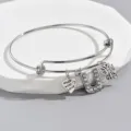 Close-up detail of adjustable silver wire bangle with rhinestone letter U and butterfly charms. - Style U