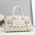 Detailed view of cream-colored PU leather handbag with monogram print and gold hardware. - 32.5x11x20cm / Off White