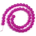 Primo piano di perline rotonde in vetro magenta brillante per accessori fai da te. - Rosso rosa