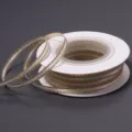 Close up detail view of white polyester ribbon featuring sparkling gold edges on spool. - 3mm 18 Meters/Roll 25g/Roll / Beige