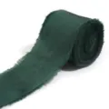 Primo piano di nastro in raso verde scuro con frange, morbida texture di tessuto in rotolo. - Verde smeraldo