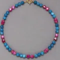 Dettaglio in primo piano della collana di perle in pietra naturale colorata con chiusura a T dorata. - Collana / 43cm / Misto Rosso/Blu