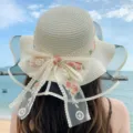 Vue détail du chapeau de paille d'été avec nœud en dentelle florale et bord en filet. - Taille unique (convient pour 56-58 cm) / Ruban à fleurs - Crème