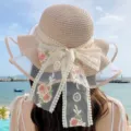 Vue détaillée du chapeau de paille de plage d'été avec un élégant nœud en dentelle et filet. - Taille unique (convient pour 56-58 cm) / Ruban à fleurs - Rose