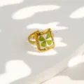 Vista detallada del anillo de acero inoxidable chapado en oro con trébol transparente. - Anillo Cuadrado Irregular con Trébol y Flor Preservada (506)