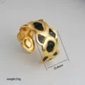 Gold-tone metal cuff bracelet with black enamel abstract pattern, chic open design, 33.8mm. - 43